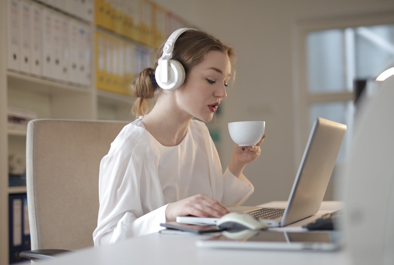 phụ nữ-sử dụng máy tính xách tay tại văn phòng trong khi uống cà phê và sử dụng tai nghe-kỹ năng khó